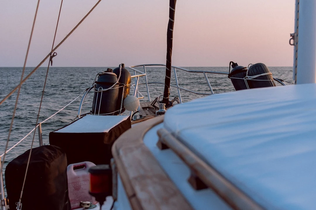 A sailing yacht's foredeck at dusk, with sail cover and fenders ready before departure.