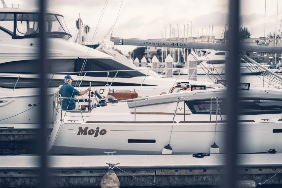A yacht captain at the helm of a crewed charter yacht, steering out of a marina.